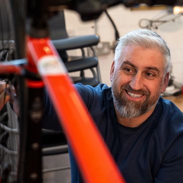 Smiling man fixing a red bicycle.