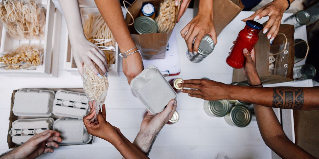People sorting food donations including canned goods and pasta.