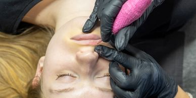 Close-up of a woman receiving a cosmetic lip tattoo procedure.