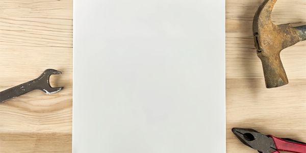 Blank white paper on wooden table surrounded by tools.