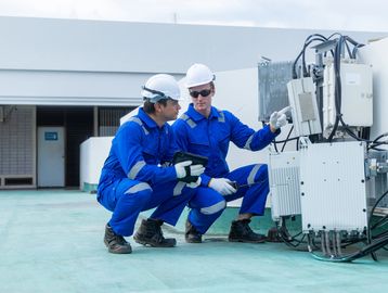 Two workers inspecting outdoor electrical equipment.