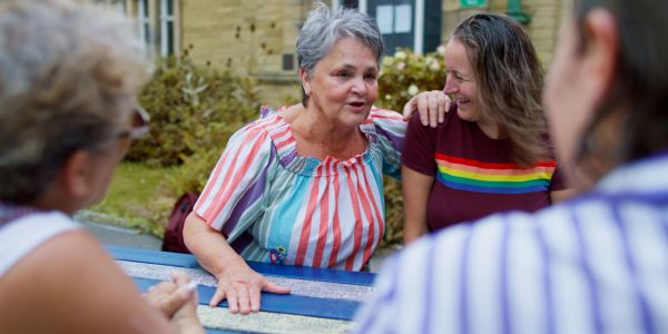 Two women sharing a heartfelt moment at a picnic table outdoors.
