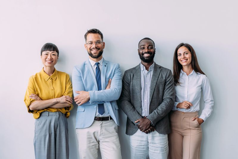 Portrait of confident business people standing together in the office. Multiracial group of business persons standing side by side in modern office.