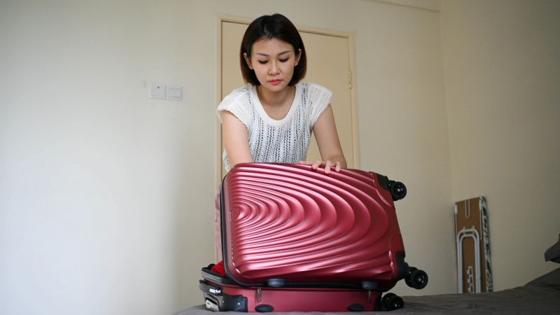 A young woman gets ready to leave, finishing her packing routine in a hotel room.