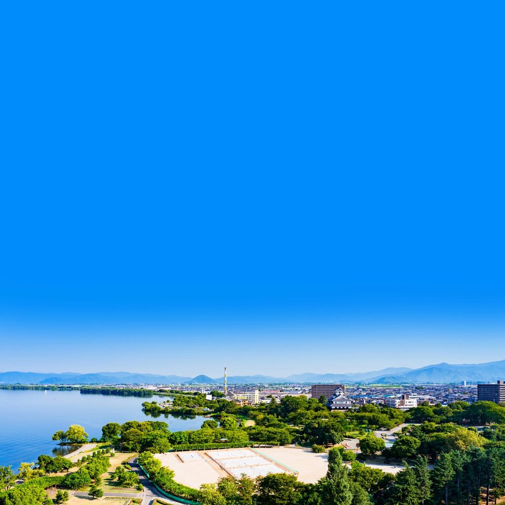 A vibrant lakeside cityscape with lush greenery and clear blue skies.