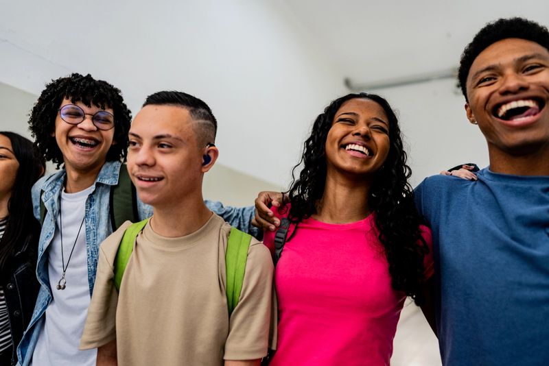 Happy teenage students laughing together in school hallway - including people with Down syndrome