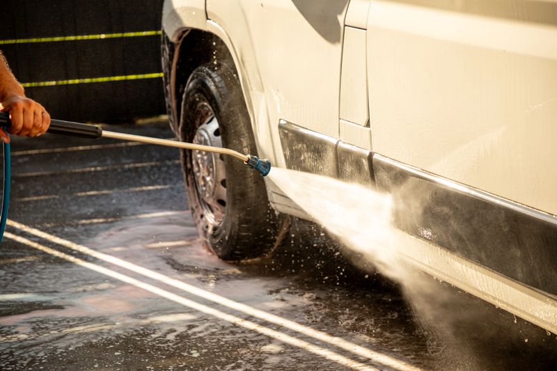 High-pressure cleaning of a van on a sunny day, showcasing advanced car wash technology, thorough maintenance, and vehicle hygiene (part of the “at the car wash” series).