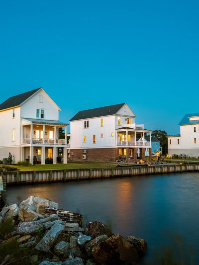 Modern waterfront houses with warm lights during twilight.