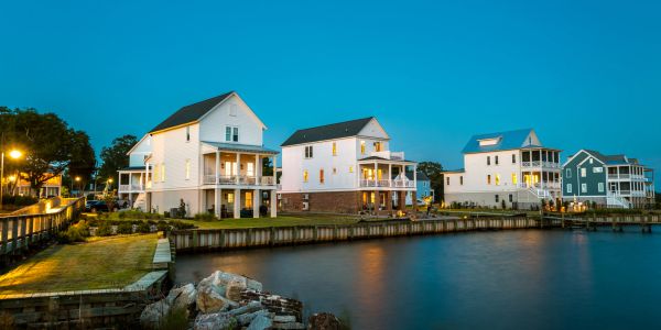 Waterfront houses at dusk with lights on.