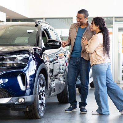 Couple excitedly examining a new car at a dealership.