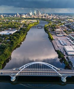 Aerial view of a city skyline with a river and modern bridge in the foreground.