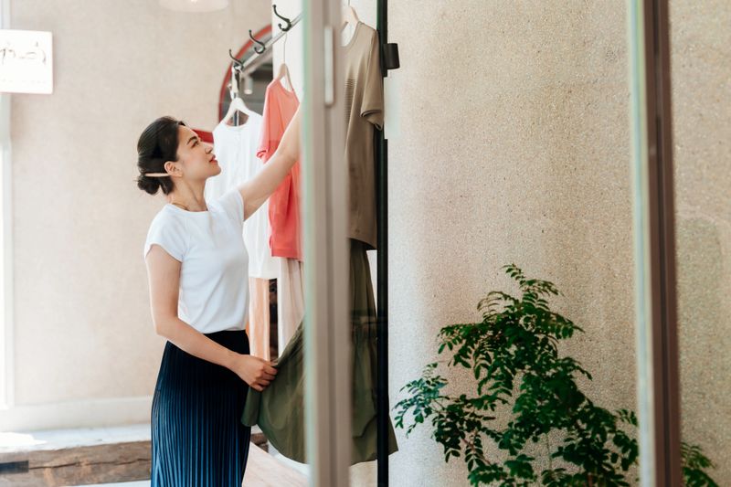 Young Asian woman choosing in a clothing store. Sale season. Seasonal shopping in the clothing store.