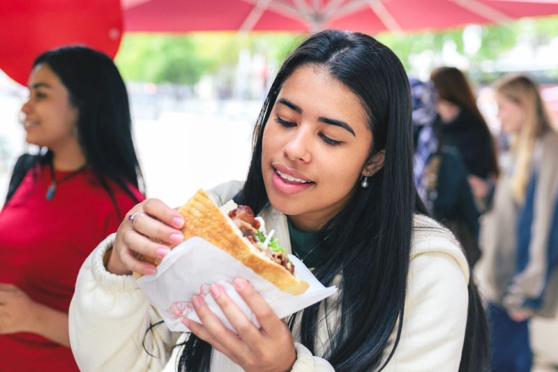 young woman eating doner kebab on street in berlin city