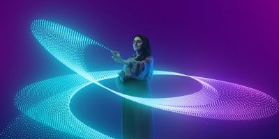Woman interacts with swirling digital light patterns.