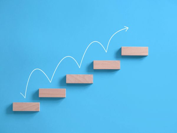 Wooden blocks arranged as ascending steps with an arrow.