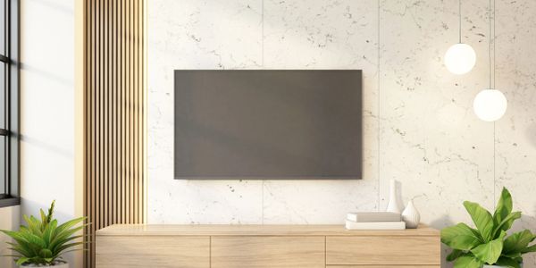 Modern TV mounted on marble wall with wooden cabinet and green plants.