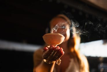 Woman holding a smoking incense burner.