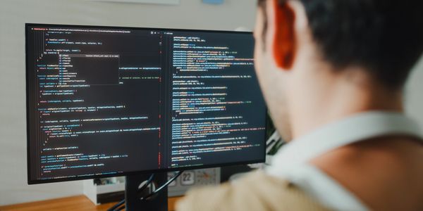 Person coding on a computer screen with complex programming language.