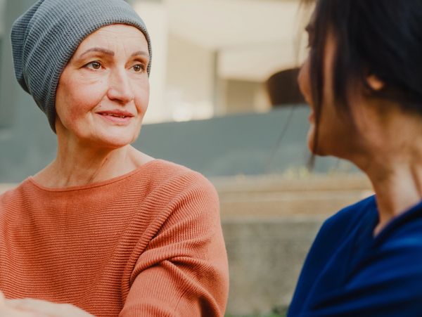 Two women engaged in a heartfelt conversation outdoors.