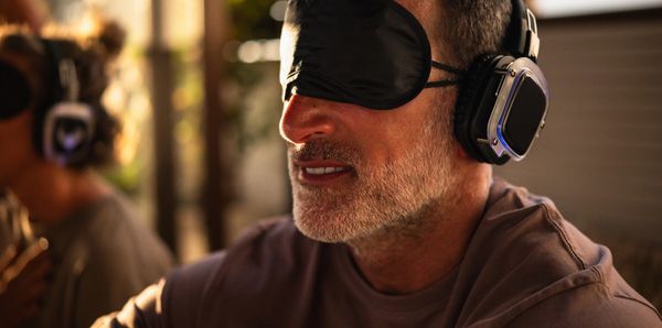 Man wearing blindfold and headphones, enjoying an immersive experience.