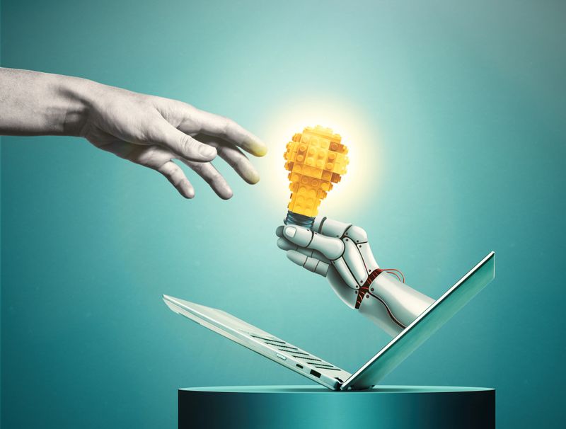 A robotic hand extends a light bulb to a person.