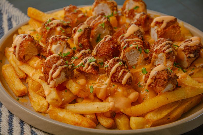 An appetizing display of classic fast food: succulent chicken wings and golden, crispy chips. This image captures the essence of comfort food, perfect for restaurant menus or food delivery services like Uber Eats. Photographed in South Africa on 02/27/2025. (image-60)