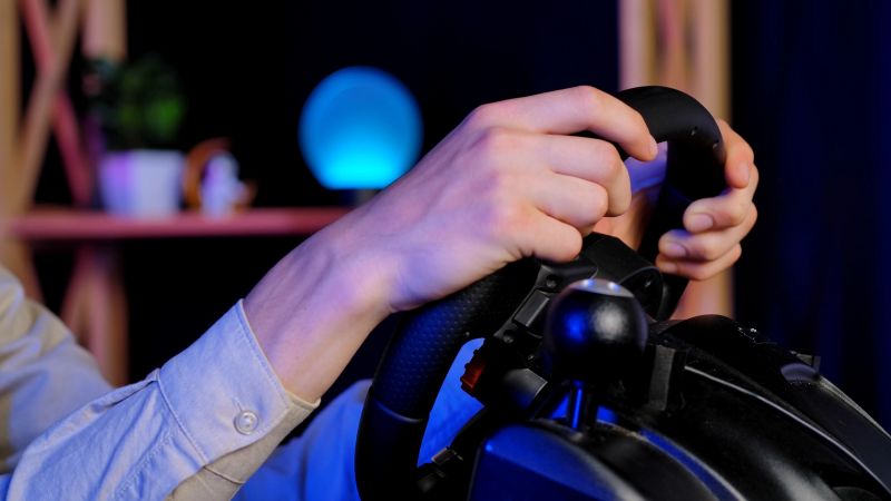 A close up image of hands gripping a gaming steering wheel, capturing the engagement in virtual racing.