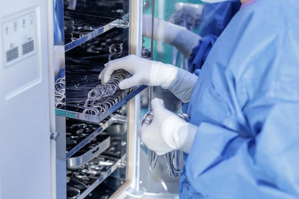 Medical staff organizing surgical instruments in sterilization cabinet.