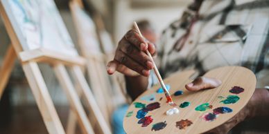 Une main tenant une palette de peinture et un pinceau.