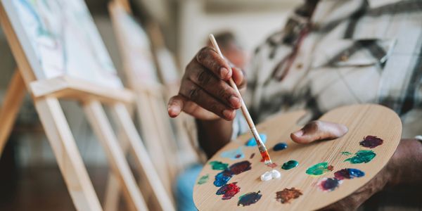Close-up of a person mixing paint colors on a palette with a brush.