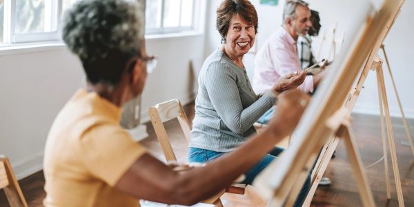Seniors painting and socializing in a bright studio.