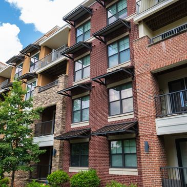 Modern brick apartment building with balconies and greenery.