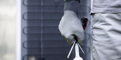 Technician holding tools in front of HVAC unit, ready for maintenance.