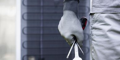 Technician holding tools near HVAC unit.