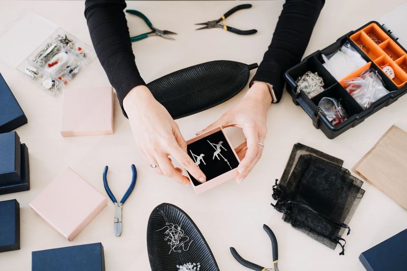 Hands presenting handmade earrings in a gift box. Showcasing sustainable jewelry design, eco-conscious packaging, and ethical craftsmanship