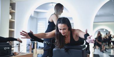 Woman exercising on Pilates reformer machine.
