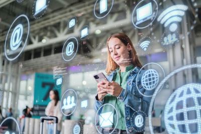 Mujer usa celular en espacio público con íconos digitales flotantes.