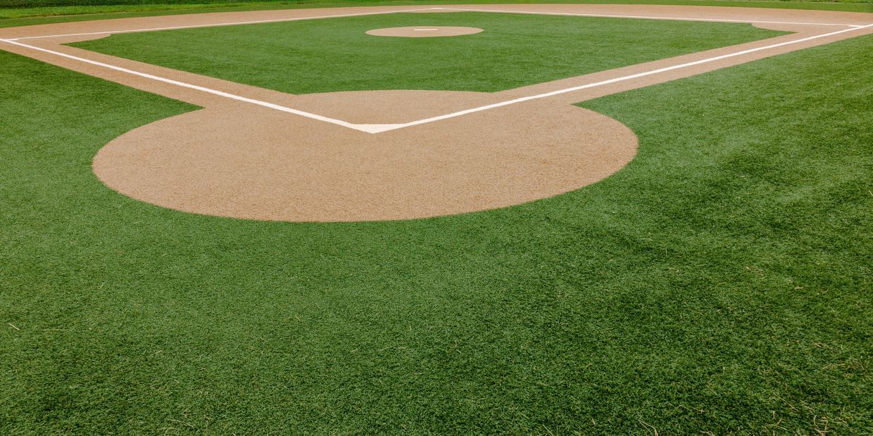 Empty baseball field with bases and green grass.