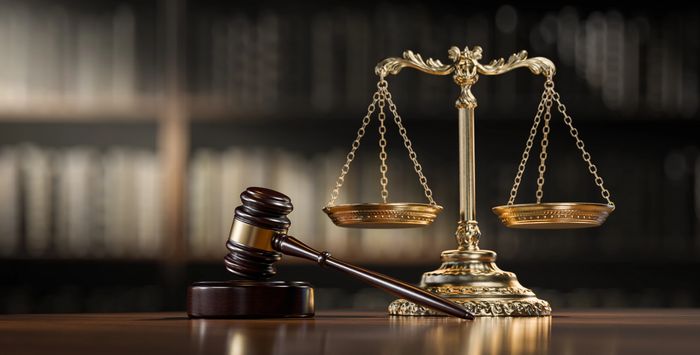 Judge's gavel and scales of justice on a wooden table.