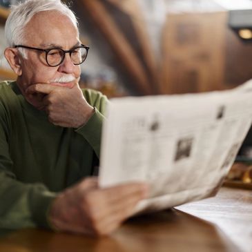 Homem idoso lendo jornal.