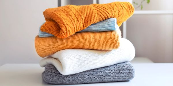 A neat stack of colorful folded sweaters on a white surface.