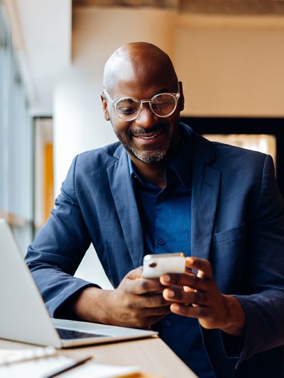 Man in a suit smiling at his phone.