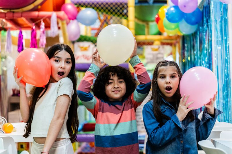 Portrait of friends playing with balloon in a party hall