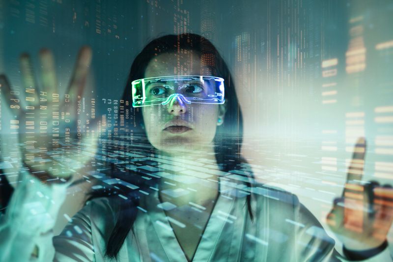 Young woman is using futuristic glasses and visual graphics during work.