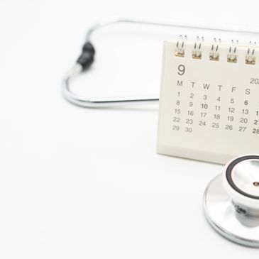 Stethoscope next to a September calendar on a white background.