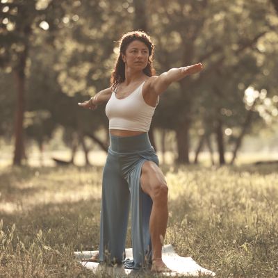 Woman practicing yoga outdoors in a warrior pose.