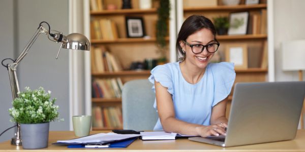 Woman working happily on her laptop at home office.