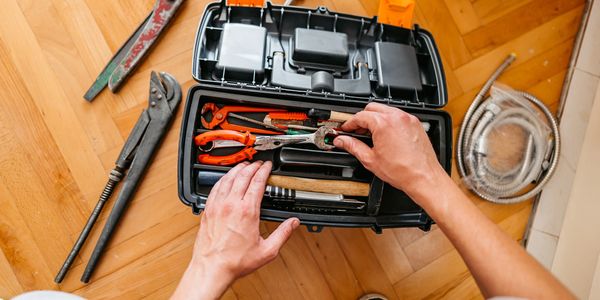 Person selecting a wrench from a toolbox filled with various tools.