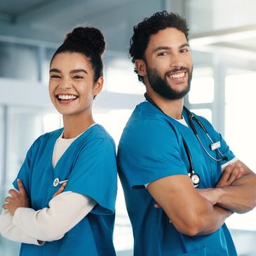 Two healthcare professionals smiling confidently in blue scrubs.