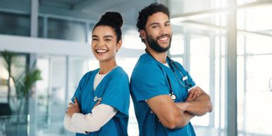 Two happy healthcare professionals standing back-to-back.